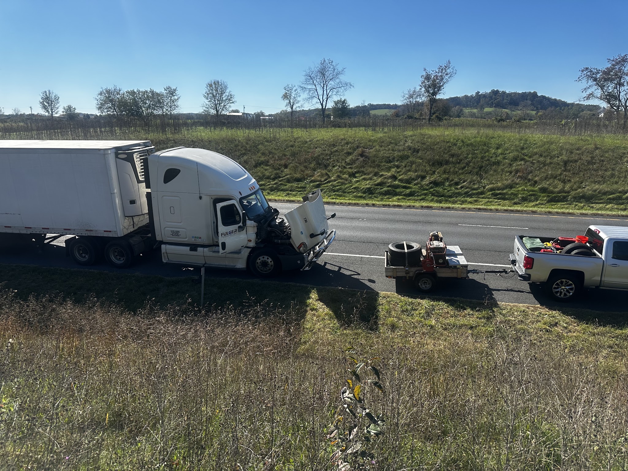 A tractor trailer pulled onto the grass shoulder of a highway