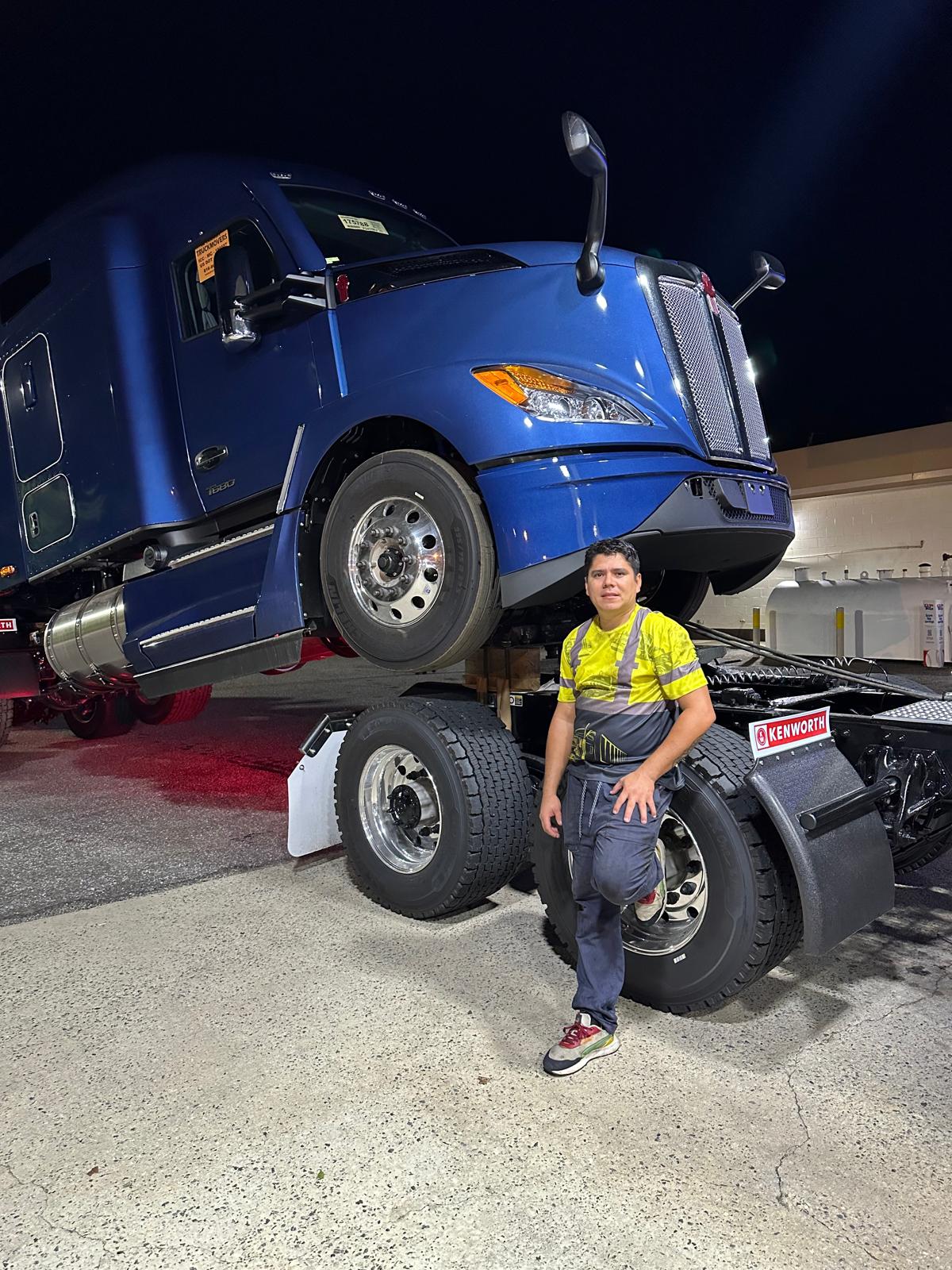 Our mechanic standing beside a blue semi tractor at night