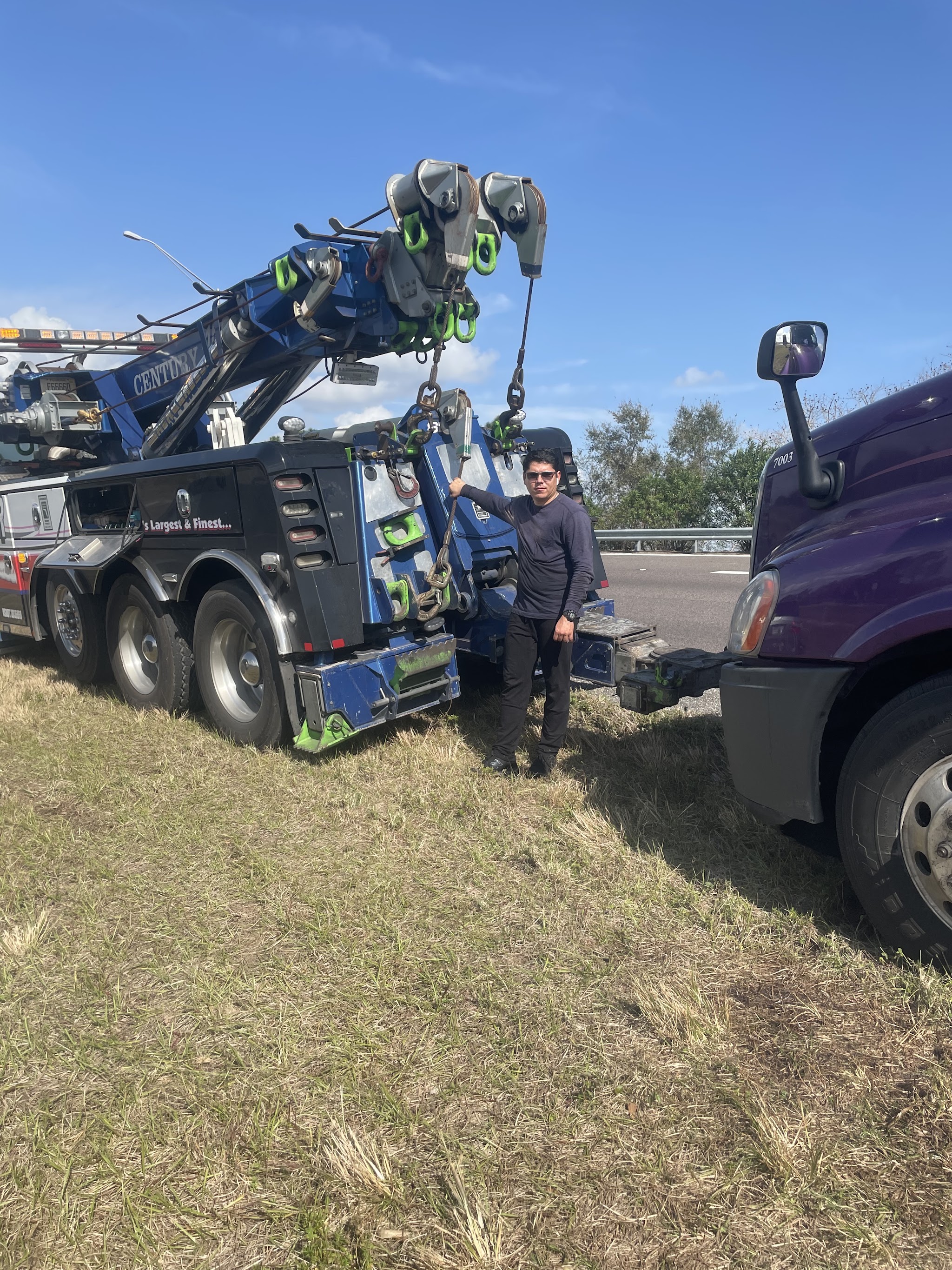 A heavy-duty wrecker lifting a truck on the roadside